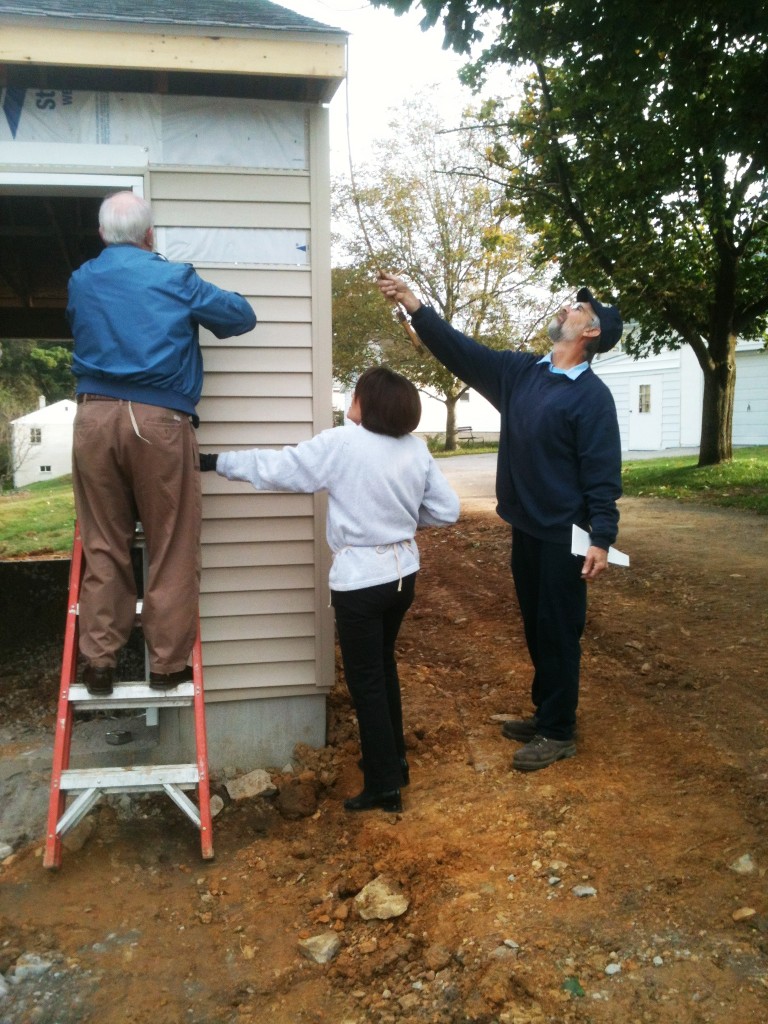 Dale and Anna Mae work on siding while Jim takes measurements.